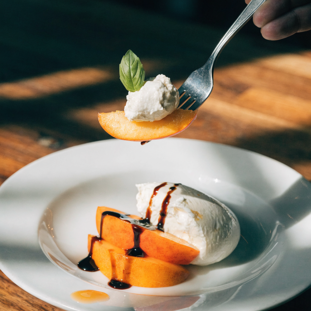 Close-up of peach burrata salad with arugula and balsamic drizzle